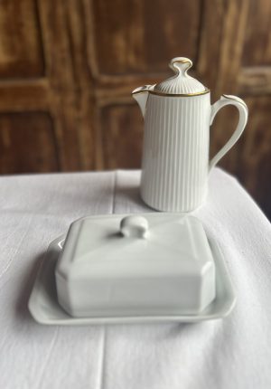 Beurrier en faïence blanche Pillivuyt Beurrier ancien chic de Méhun-sur-Yèvre Il y a des maisons qui traversent les siècles sans perdre leur âme. Pillivuyt en fait partie. Ce beurrier en faïence blanche, sobre et élégant, incarne parfaitement cet esprit : une vaisselle pensée pour durer, belle sans en faire trop, et toujours juste sur une table. Dans cette nouvelle sélection, j’ai eu envie de remettre les beurriers à l’honneur. Et celui-ci, avec son blanc lumineux et ses lignes intemporelles, s’impose comme un beau classique. • de 300 avis clients satisfaits certifiés par avis garantis ⸻ Description du beurrier blanc Pillivuyt Ce beurrier est réalisé en faïence blanche, dans un style épuré qui fait toute sa force. Le blanc traverse les modes, s’accorde avec toutes les vaisselles, et apporte cette impression de table soignée, sans jamais en faire trop. C’est un beurrier ancien de la maison Pillivuyt, une référence française dans l’univers de la céramique culinaire. Une pièce à la fois utile et décorative, qui trouve naturellement sa place sur une table du quotidien comme sur une table de fête. ⸻ Dimensions • Longueur : 18 cm • Largeur : 12 cm • Hauteur : 9 cm Un format idéal pour accueillir une motte de beurre et servir facilement à table. ⸻ État Le beurrier est en parfait état. Aucun éclat. Aucune fêle. Une très belle pièce, prête à être utilisée. ⸻ Prix et livraison 💶 Prix de vente : 20 euros 📦 Livraison possible par : • Mondial Relais • Colissimo Partout en France. ⸻ La faïence blanche, élégance du quotidien La faïence est une céramique recouverte d’un émail qui lui donne cet aspect lisse et lumineux. Depuis des siècles, elle accompagne les tables françaises. Elle est solide, agréable à l’usage, et elle supporte parfaitement la vie de tous les jours. La faïence blanche a ce pouvoir particulier : elle met en valeur ce que l’on sert. Le beurre paraît plus doré. Le pain plus appétissant. Et la table, tout simplement, plus belle. ⸻ Pillivuyt, un grand nom de la céramique française La maison Pillivuyt est fondée en 1818 à Méhun-sur-Yèvre, dans le Cher, au cœur de la France. Dès l’origine, l’entreprise se spécialise dans la fabrication de vaisselle en céramique de haute qualité, destinée aussi bien aux particuliers qu’aux professionnels. Au fil du XIXᵉ siècle, Pillivuyt développe un savoir-faire unique et met au point une porcelaine culinaire extrêmement résistante, parfois décrite comme une porcelaine hybride. Elle supporte : • les chocs thermiques, • les hautes températures du four, • les usages intensifs de la restauration et de l’hôtellerie. C’est cette robustesse, alliée à une grande élégance, qui fait la réputation de la marque. Très tôt, les pièces Pillivuyt équipent les grandes tables, les hôtels et les restaurants exigeants. Deux siècles plus tard, la manufacture est toujours installée à Méhun-sur-Yèvre. Elle incarne un véritable patrimoine industriel et artisanal français, reconnu pour la qualité et la longévité de ses productions. Posséder une pièce Pillivuyt, c’est donc faire entrer chez soi un peu de cette histoire. ⸻ Pourquoi choisir ce beurrier Pillivuyt ? Choisir ce beurrier, c’est choisir : • une pièce issue d’un savoir-faire français du XIXᵉ siècle, • un beau classique blanc, chic et intemporel, • une vaisselle pensée pour durer dans le temps, • un objet utile et décoratif, • une touche d’élégance simple sur la table. C’est le genre d’objet que l’on garde longtemps. Et que l’on aime ressortir. ⸻ Mon avis de brocanteuse Je le dis souvent, et je le pense vraiment : la vaisselle blanche, c’est toujours une valeur sûre. Elle traverse les époques sans jamais se lasser. Elle va avec tout. Et elle donne tout de suite une allure soignée à la table. Un beurrier, en plus, c’est un détail qui change tout. C’est hyper chic au quotidien, et encore plus joli sur une table de fête. Pour moi, c’est un objet que l’on s’offre pour se faire plaisir, parce qu’on aime les belles choses simples. Ce beurrier Pillivuyt, je le trouve parfait pour ça. ⸻ Avis clients – La brocante bucolique.fr • de 300 avis clients satisfaits certifiés par avis garantis ⭐⭐⭐⭐⭐ “Objets toujours magnifiques et descriptions très fidèles. Un vrai plaisir.” – Claire ⭐⭐⭐⭐⭐ “Très belle vaisselle, envoi soigné. Je recommande sans hésiter.” – Sophie ⭐⭐⭐⭐⭐ “Des pièces pleines de charme et d’histoire. J’adore.” – Marc ⭐⭐⭐⭐⭐ “Chaque commande est une découverte. Merci pour ces trésors.” – Isabelle ⭐⭐⭐⭐⭐ “Service parfait et objets superbes pour ma table.” – Julien ⸻ FAQ – Beurrier en faïence blanche Pillivuyt Ce beurrier est-il ancien ? Oui, il s’agit d’un beurrier ancien de la maison Pillivuyt, issue d’une production du XIXᵉ ou début XXᵉ siècle. Peut-on l’utiliser au quotidien ? Oui, il est parfaitement adapté à un usage quotidien comme aux repas de fête. Qu’est-ce qui fait la réputation de Pillivuyt ? Pillivuyt est reconnue depuis 1818 pour sa porcelaine culinaire très résistante, utilisée dans l’hôtellerie et la restauration. La faïence est-elle solide ? Oui, surtout chez Pillivuyt, où la vaisselle est pensée pour durer et supporter un usage intensif. Le beurrier est-il en bon état ? Oui, il est en parfait état, sans éclat ni fêle. Est-ce un bel